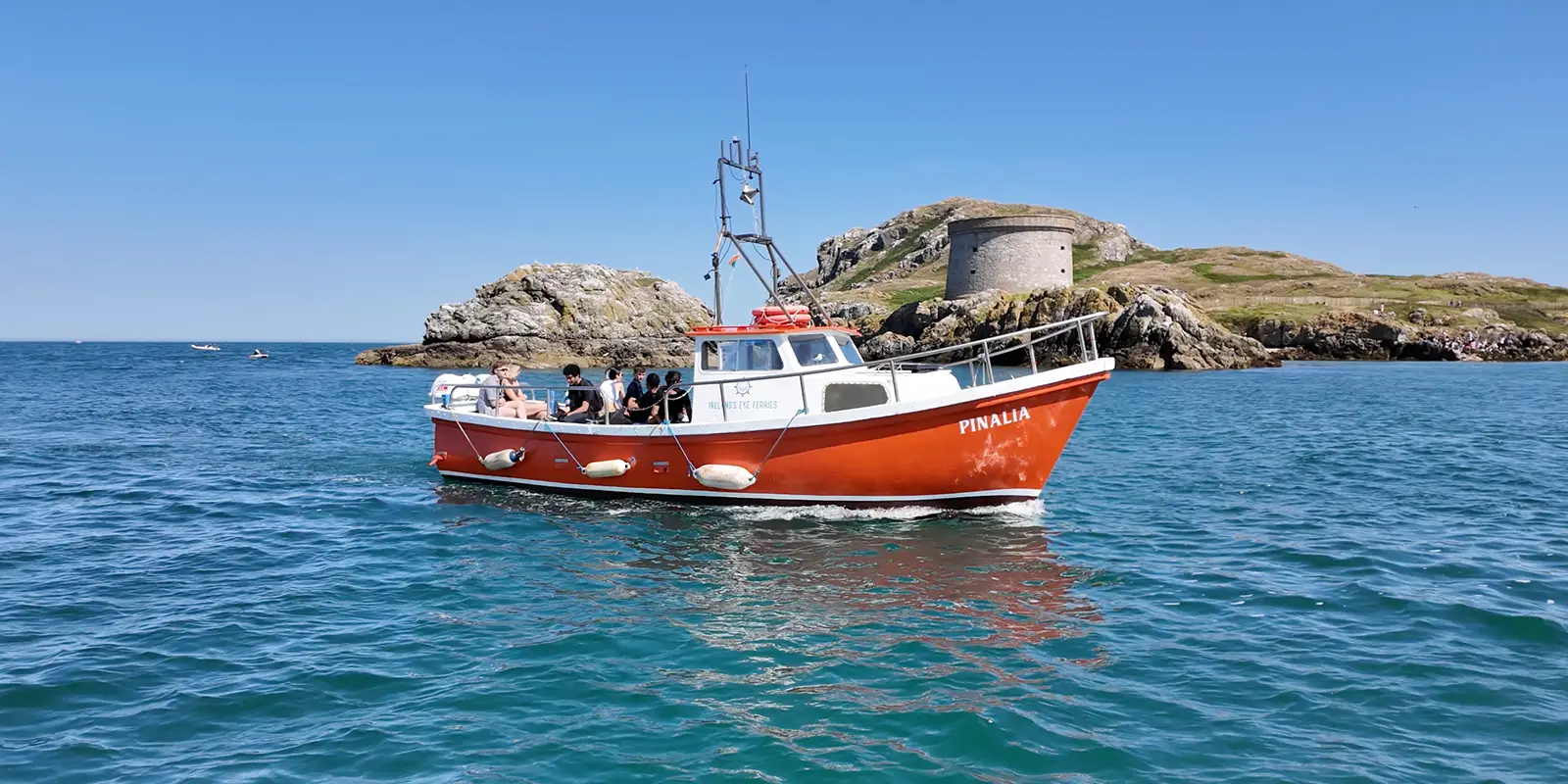 Boat with passengers passing Irelands Eye Martello Tower