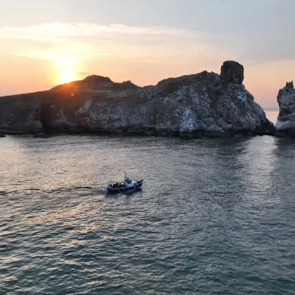 Ireland's Eye Ferry at Sunset in front of the island sea stacks at sunset.