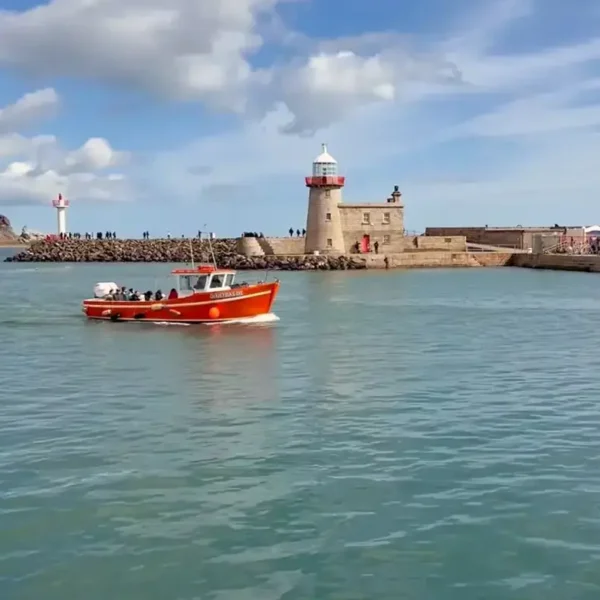 Irelands Eye Ferry enters Howth Harbour, with lighthouses and the pier in the background.