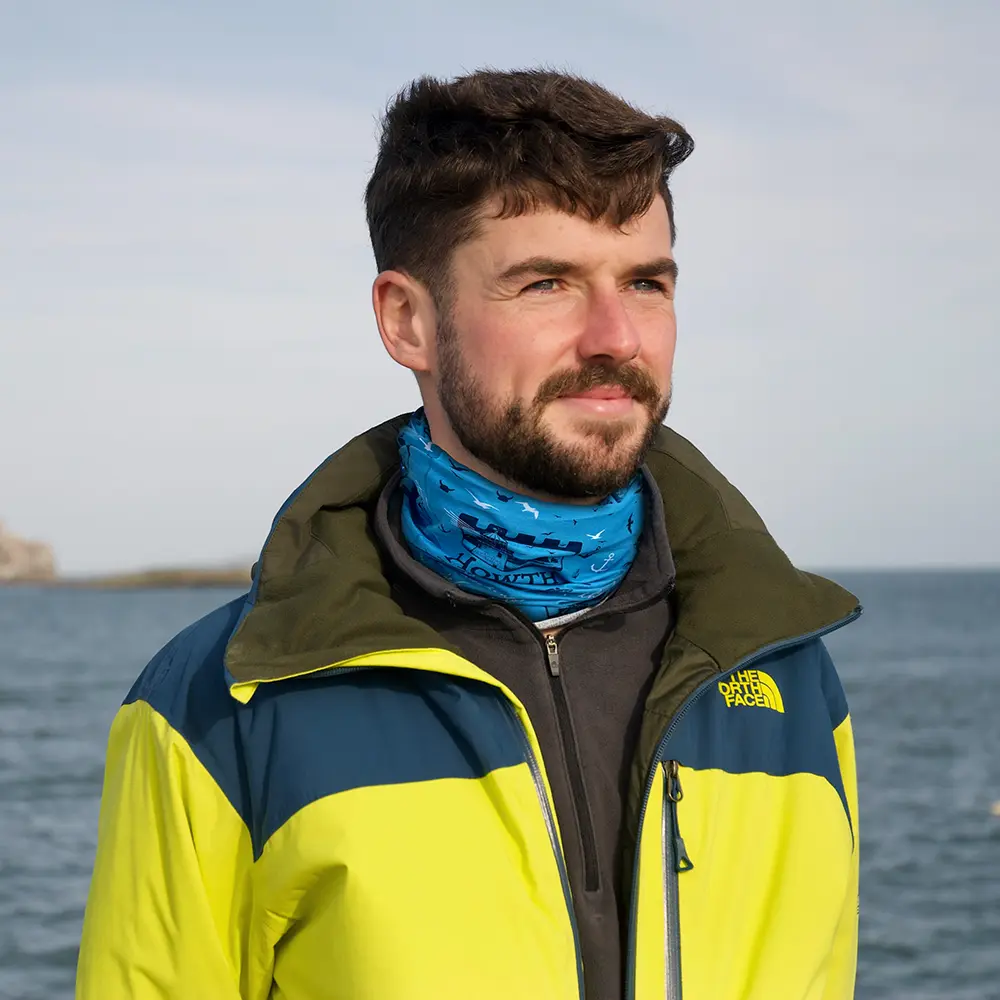 Man with yellow and Navy outdoor jackey wearing a Howth Original BUFF Blue Neck scarf.