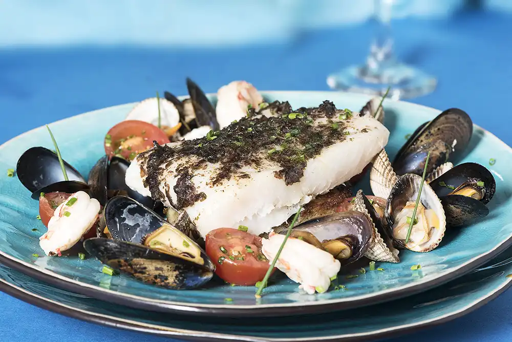 Fish dinner with Mussels on blue plate, with blue background.