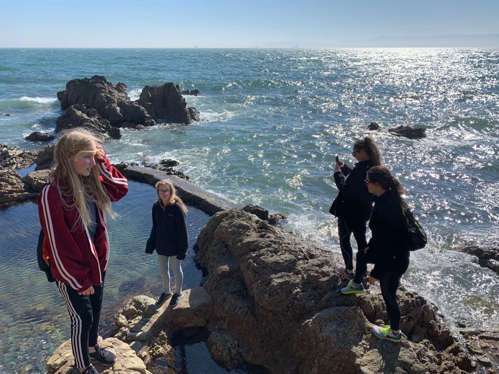 Girl hiking in Howth. Down on the shoreline on a sunny but windy day